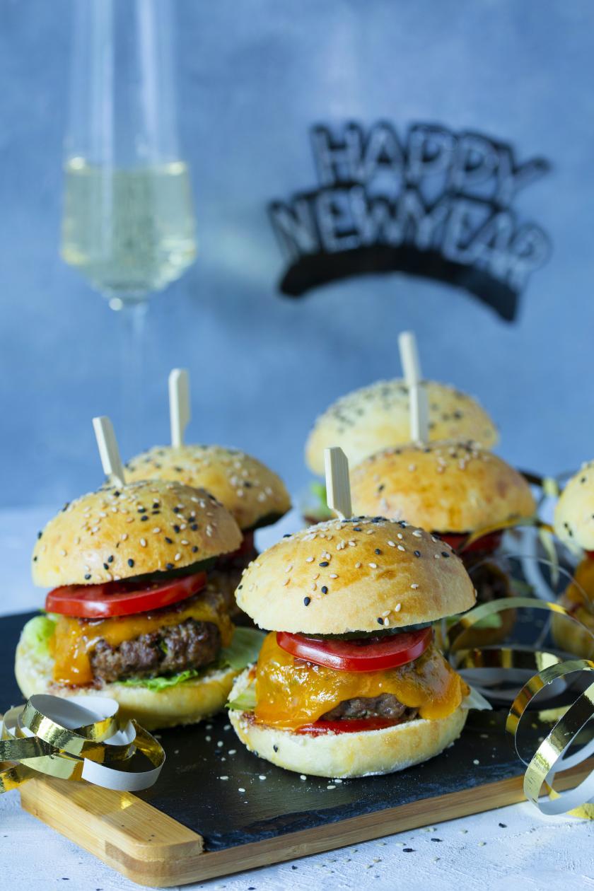 Mehrere Mini-Burger auf einem Teller mit Silvester-Deko.