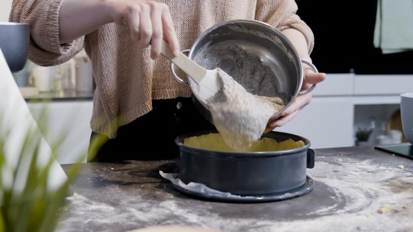 Die Füllung für den Mohnkuchen mit Schmand wird auf den Teigboden in der Springform gegeben.