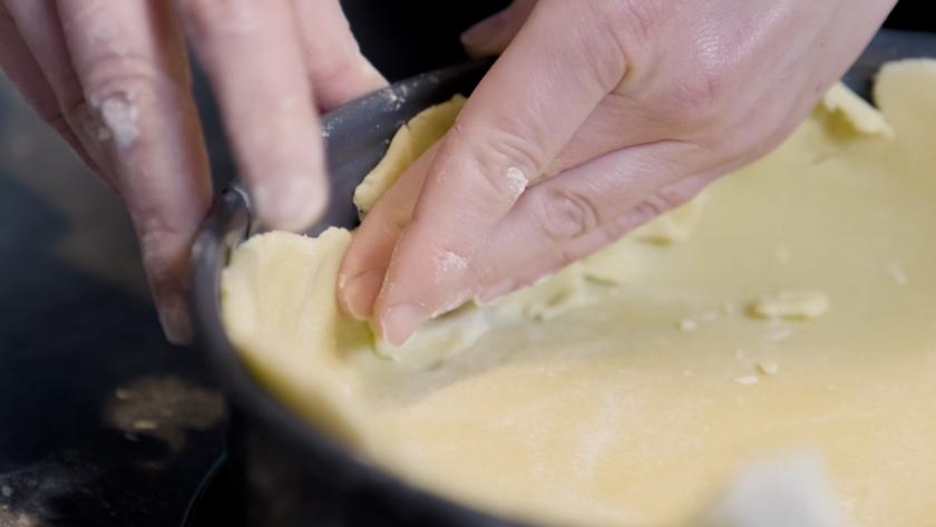 Springform wird mit Mürbeteig ausgekleidet und ein Rand hochgezogen.