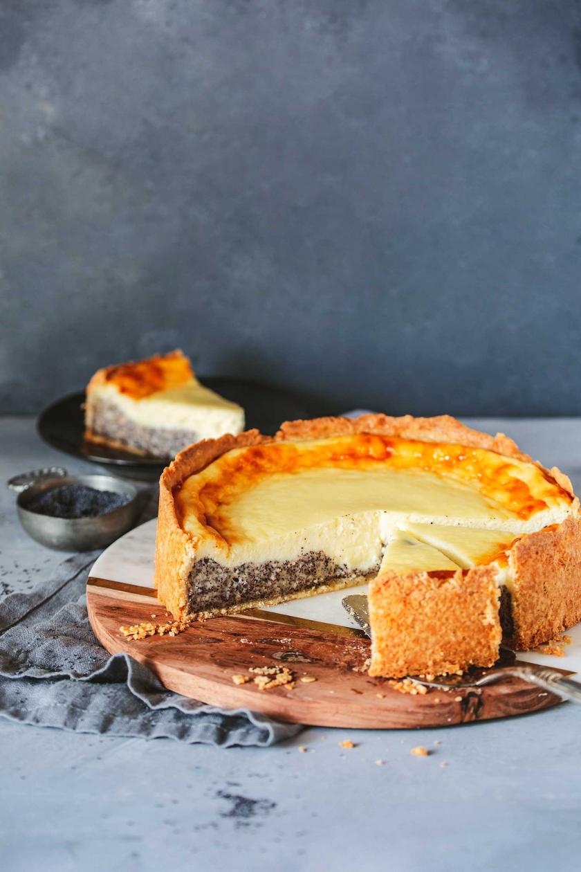 Mohnkuchen mit Schmand angeschnitten auf einer Kuchenplatte.