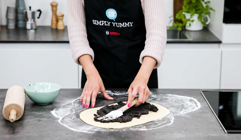 Der Teig der Mohnschnecke wird mit der Füllung bestrichen.