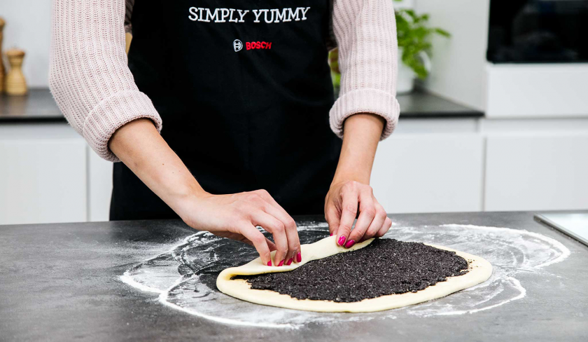 Der Teig für die Mohnschnecke wird aufgerollt.