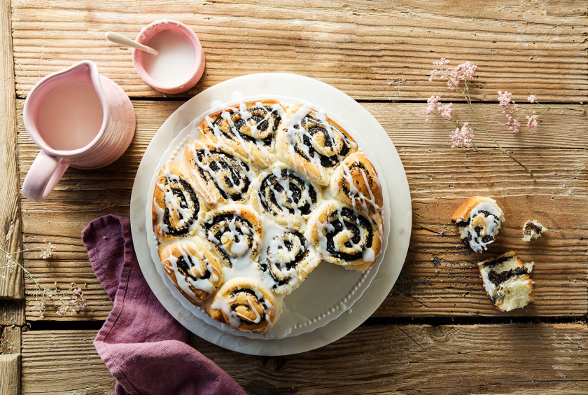 Mohnschnecke auf einem Teller angerichtet und mit Guss garniert.