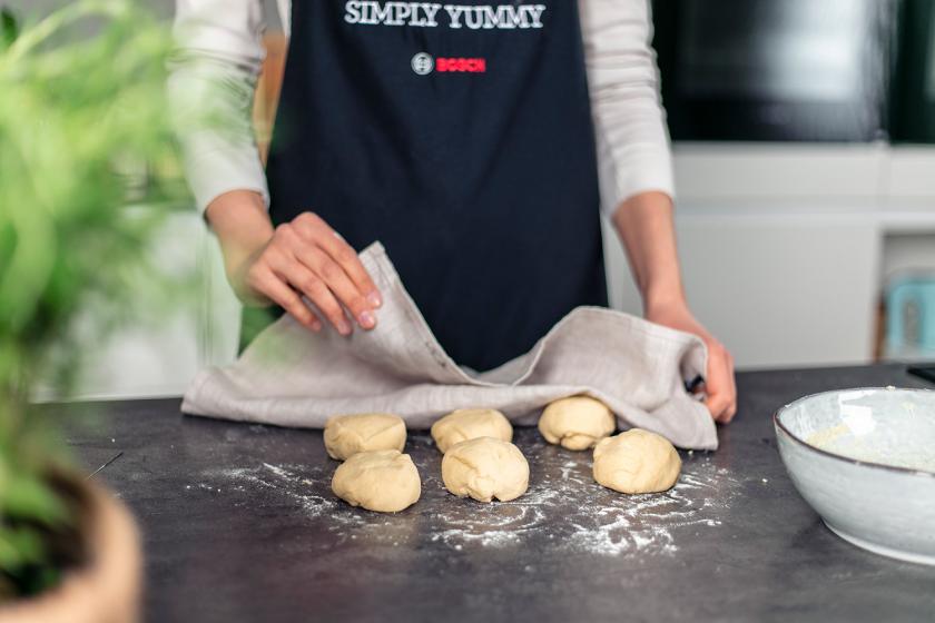 Der Teig für das Naan Brot liegt in 6 Portionen auf der Arbeitsfläche und wird abgedeckt.