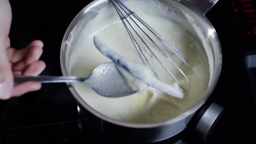 Die Vanilleschote wird mit einem Löffel aus dem Pudding gehoben.