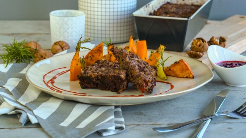 Zwei Scheiben Nussbraten mit Karotten und Kürbis auf einem Teller.