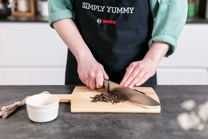 Zartbitterschokolade wird auf einem Brettchen gehackt.