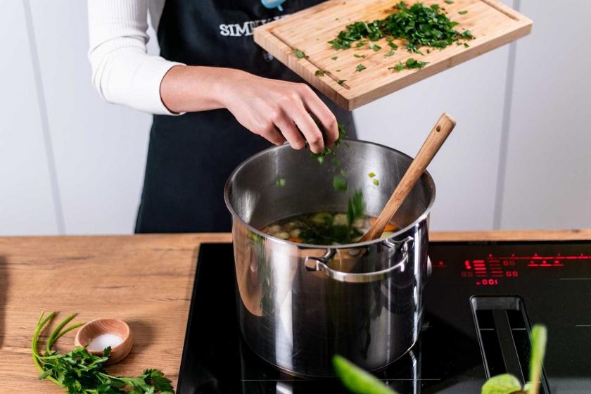 Auf Omas Hühnersuppe im Topf wird Petersilie gestreut.