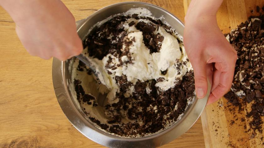 Oreo-Kekse werden unter die Creme für den Oreo-Kuchen gerührt.