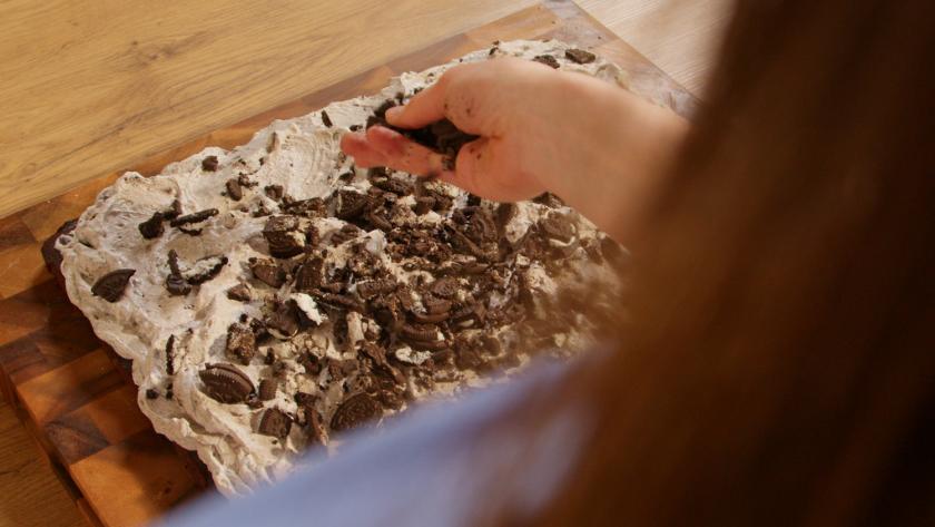 Oreo-Brösel werden auf dem fertigen Oreo-Kuchen verteilt.