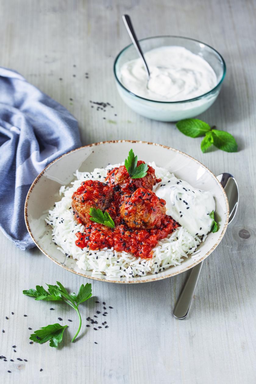 Orientalische Hackbällchen auf Reis in einem Teller mit angelegtem  Löffel.
