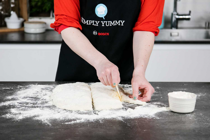 Die Teigkanten vom Ciabatta Teig werden mit einem Messer abgeschnitten.