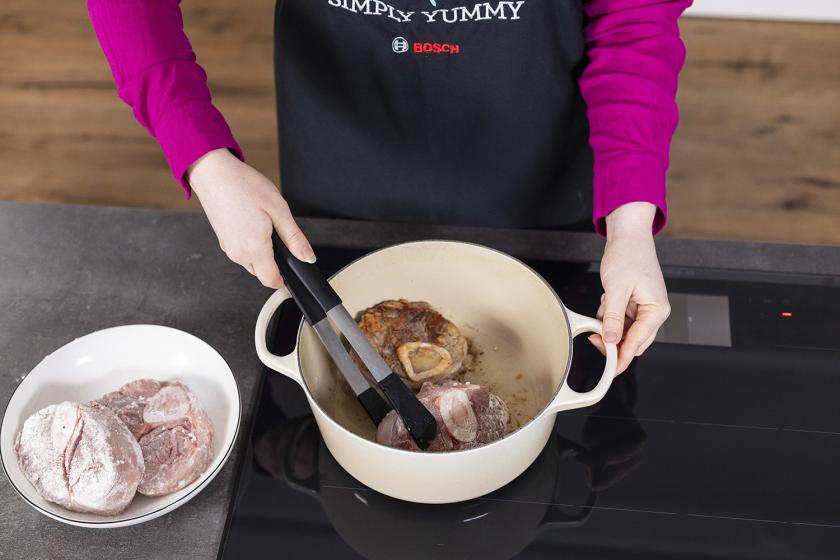 Ossobuco wird in einem Bräter angebraten.