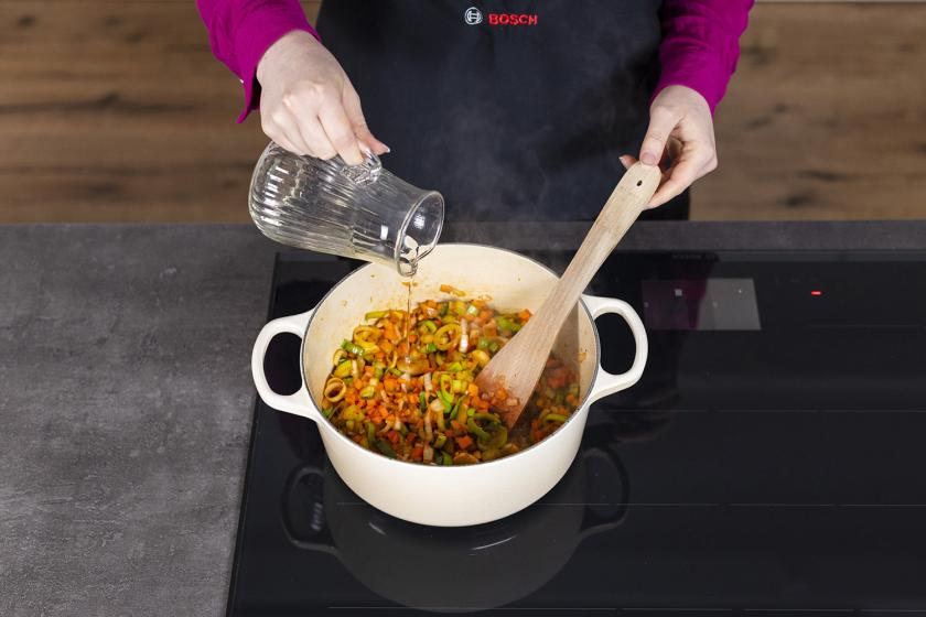 Wein wird zum Gemüse in den Topf gegeben.