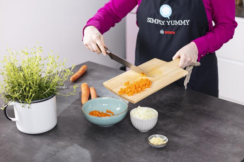 Gewürfelte Möhren werden in eine Schale  gefüllt.