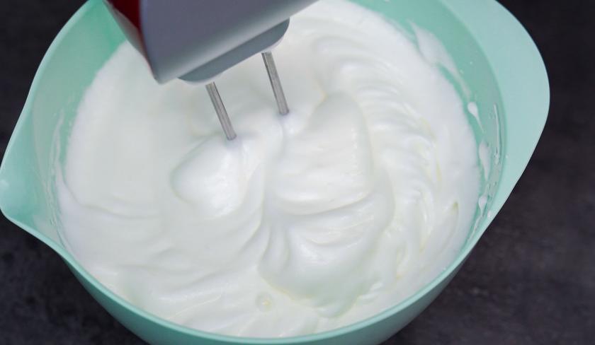 Für den Osterkuchen vom Blech wird Sahne in einer Rührschüssel aufgeschlagen.