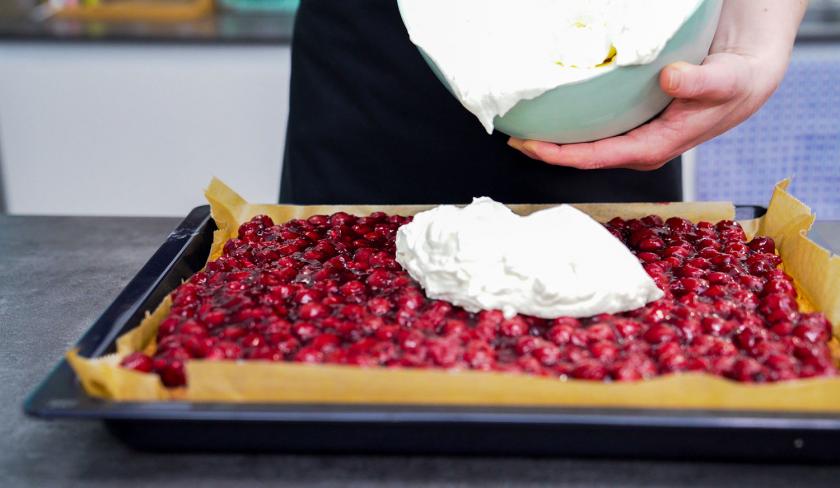 Auf den Osterkuchen vom Blech wird Sahne verteilt.