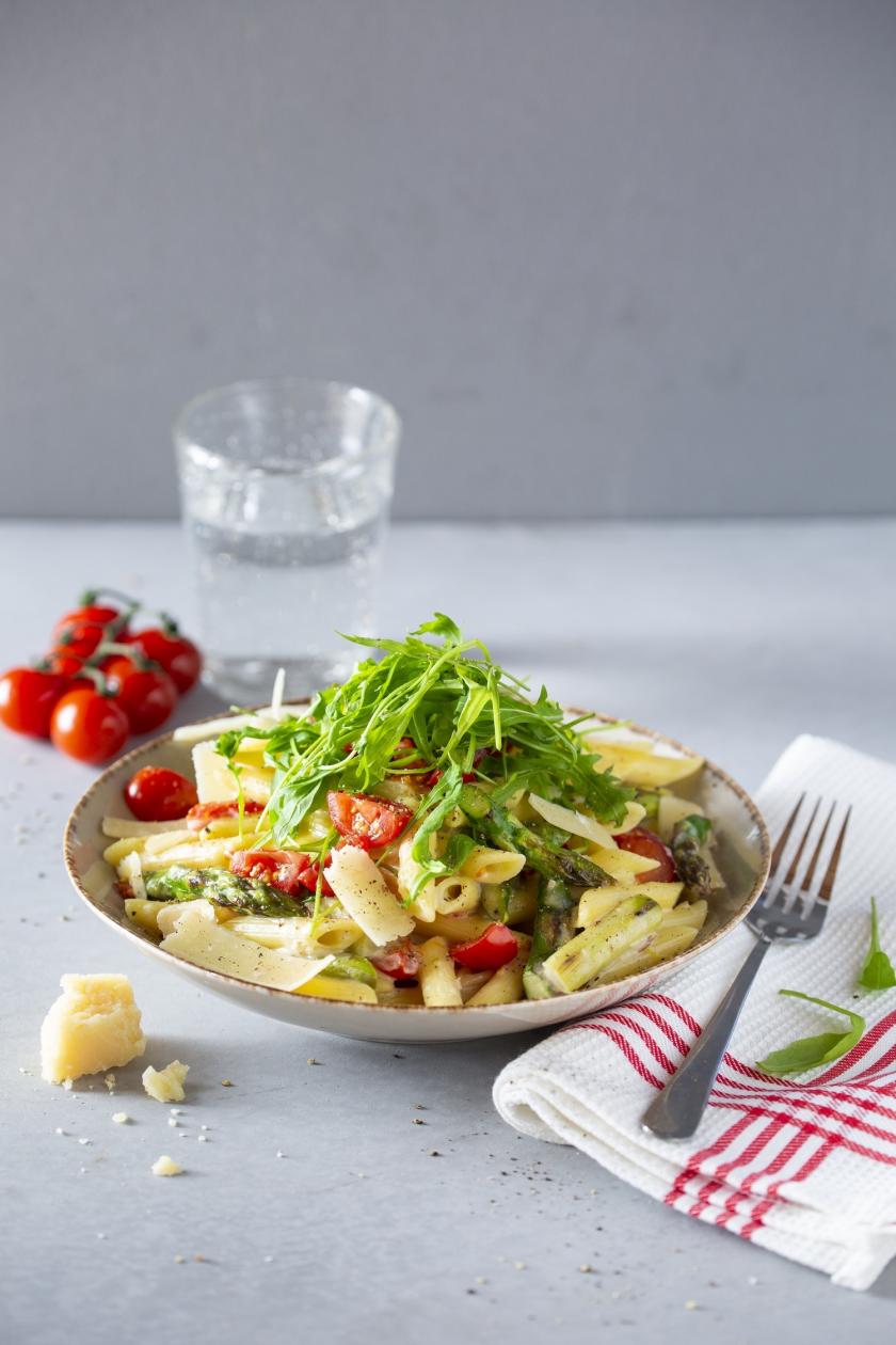 Pasta mit grünem Spargel und Rucola auf einem Teller angerichtet.