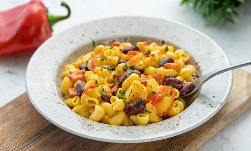 Pasta mit Bohnen, roter Paprika und Nacho-Käsesauce in einem Teller.