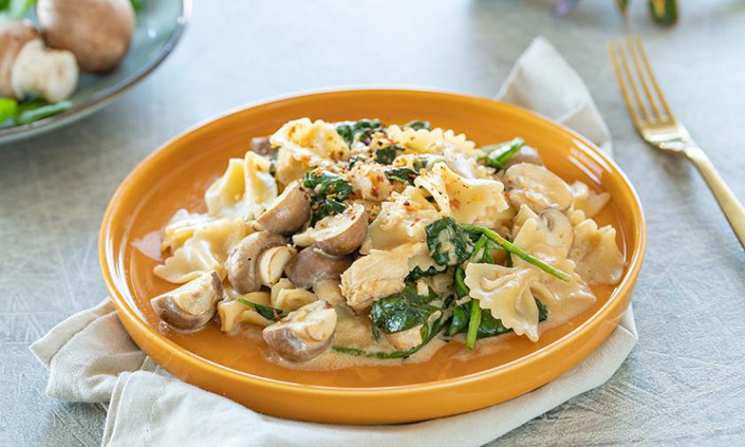Pasta mit Hühnchen Spinat und Champignons auf einem tiefen Teller