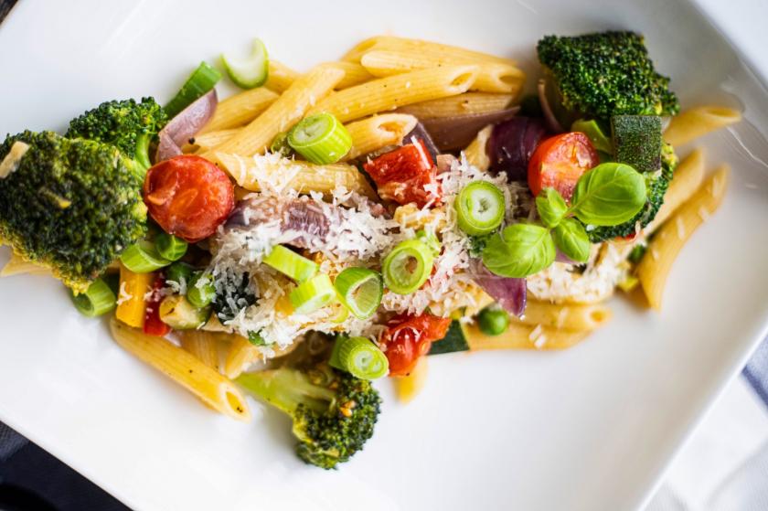 Pasta Primavera mit viel buntem Gemüse auf weißem Teller.