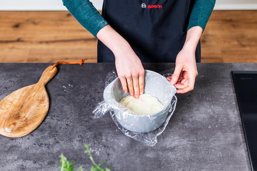 Pudding in einer Schüssel wird mit Frischhaltefolie abgedeckt.