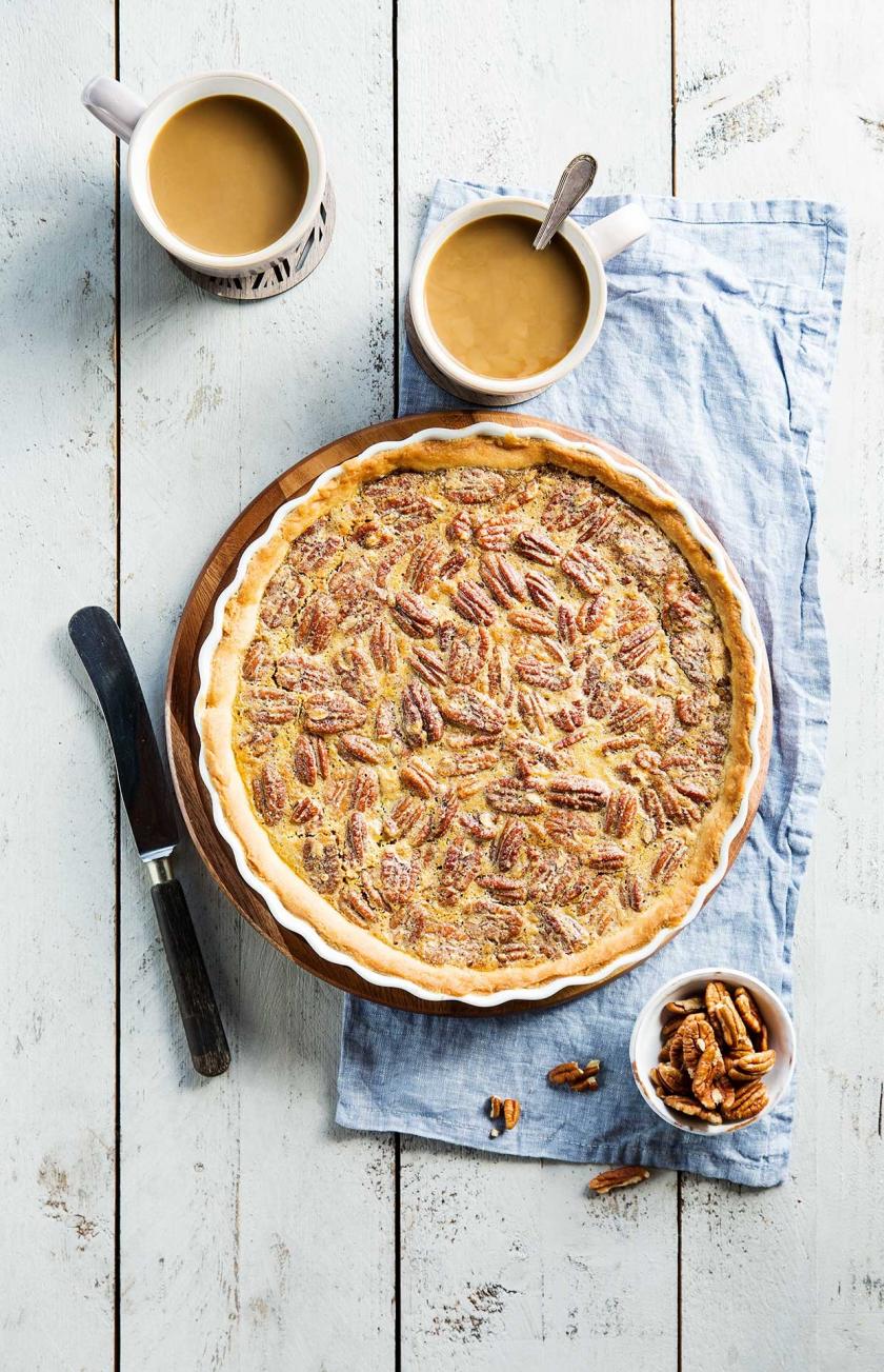 Pecan Pie in der Form auf einem Tisch mit zwei Kaffeetassen.