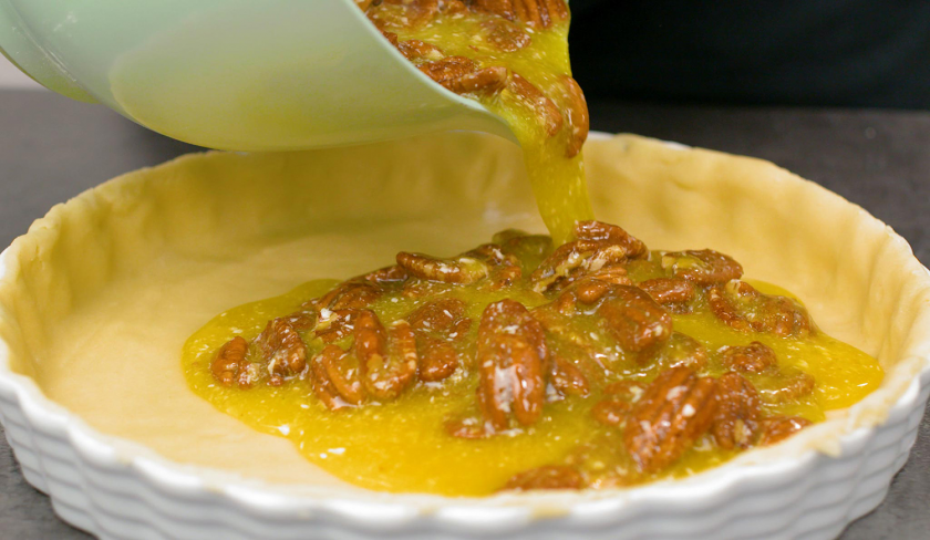 Die Füllung von dem Pecan Pie wird auf den vorbereiteten Boden in der Form gegossen.