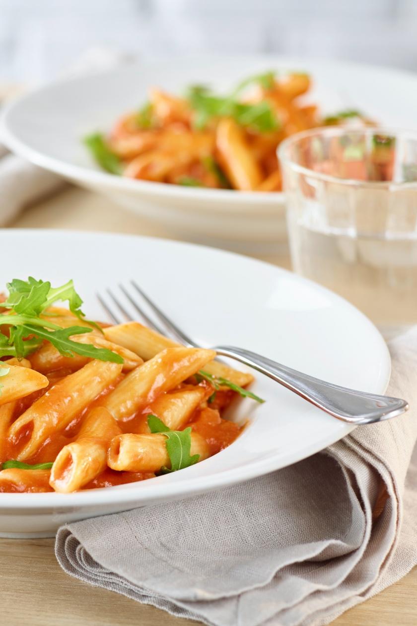 Penne-Pomodoro mit Gorgonzola und Rucola in einem Teller angerichtet.