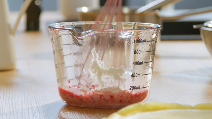 Kirschsaft wird mit Puddingpulver in einem Messbecher verrührt.