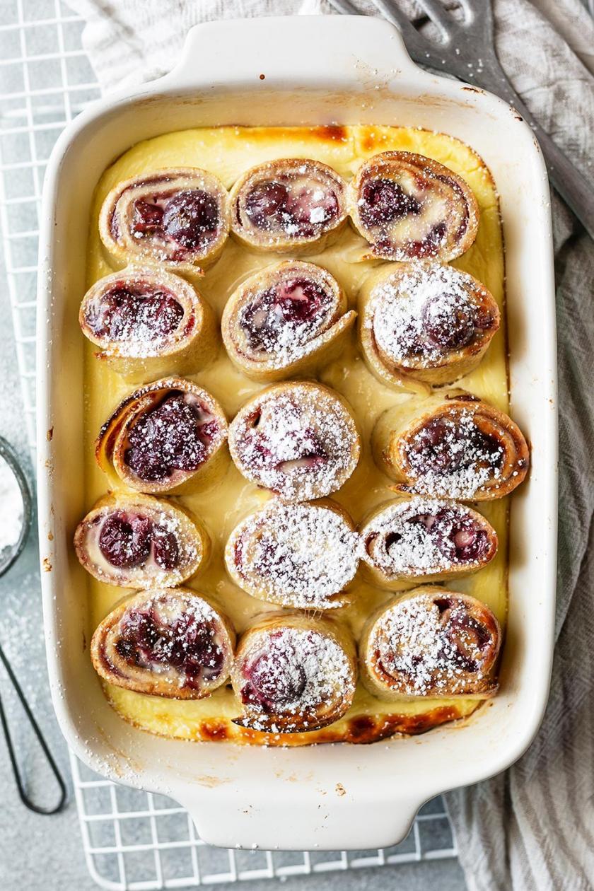 Pfannkuchen Auflauf mit Kirschen und Puderzucker in einer Auflaufform.