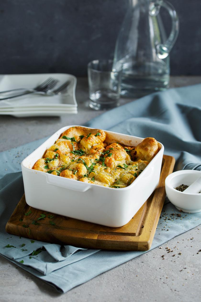 Pfannkuchen-Auflauf in einer Auflaufform auf einem Holzbrett.