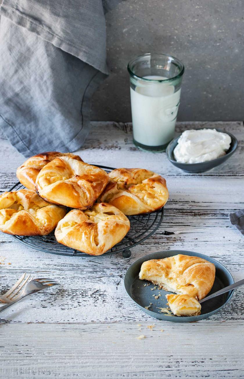 Mehrere Quarktaschen auf einem Teller, eine angebrochene Quarktaschen davor.