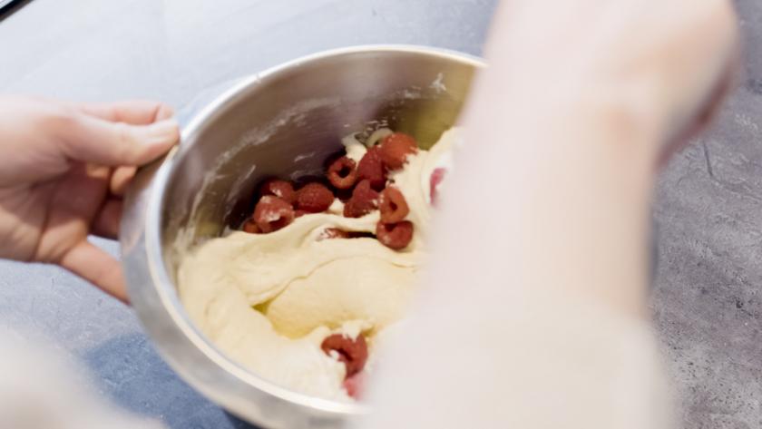 Himbeeren werden unter den Teig für die Raffaello-Muffins gehoben.