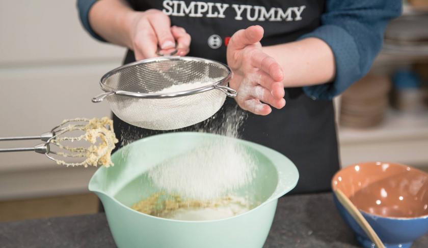 Mehl wird für den Teig der Apfel-Zimt-Muffins in eine Rührschüssel gesiebt.