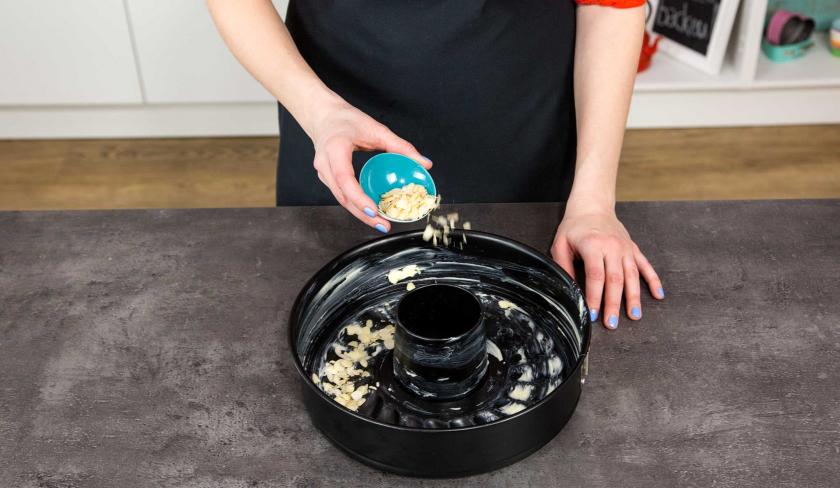 Eine Backform wird mit Mandelblättchen ausgestreut.