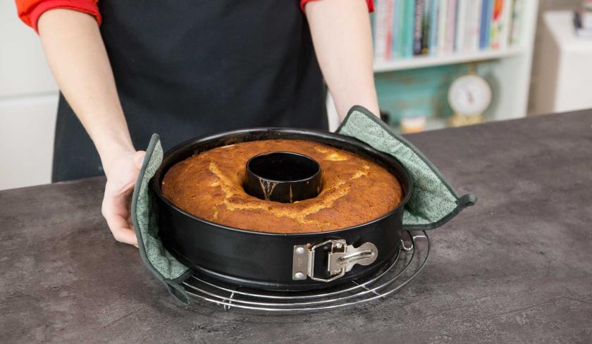 Der Apfelkuchen mit Buttermilch wird auf ein Kuchengitter gestellt.