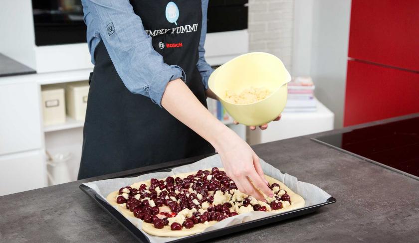 Der Streuselteig wird über den Kirsch-Streuselkuchen verteilt.