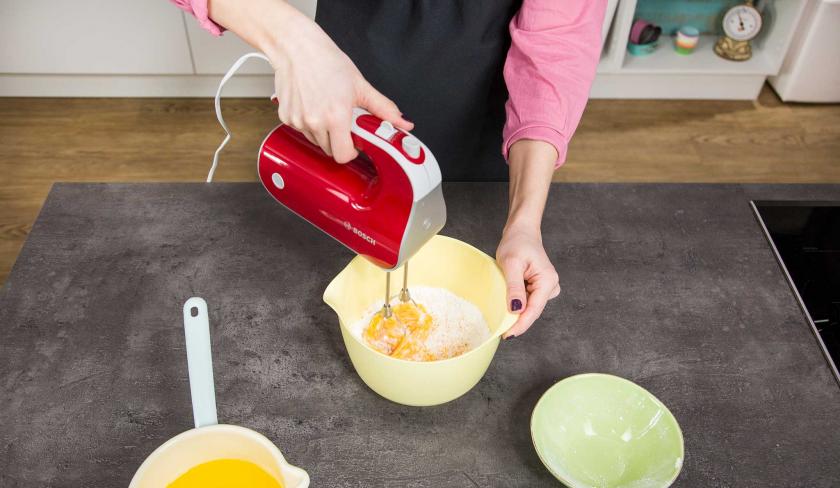 Für den Teig für den Zauberkuchen werden Eier mit Puderzucker mit einem Handmixer verrührt.