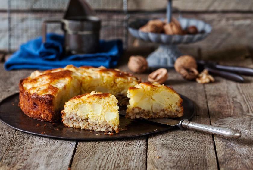 Apfel-Walnuss-Kuchen auf einer Kuchenplatte angeschnitten.