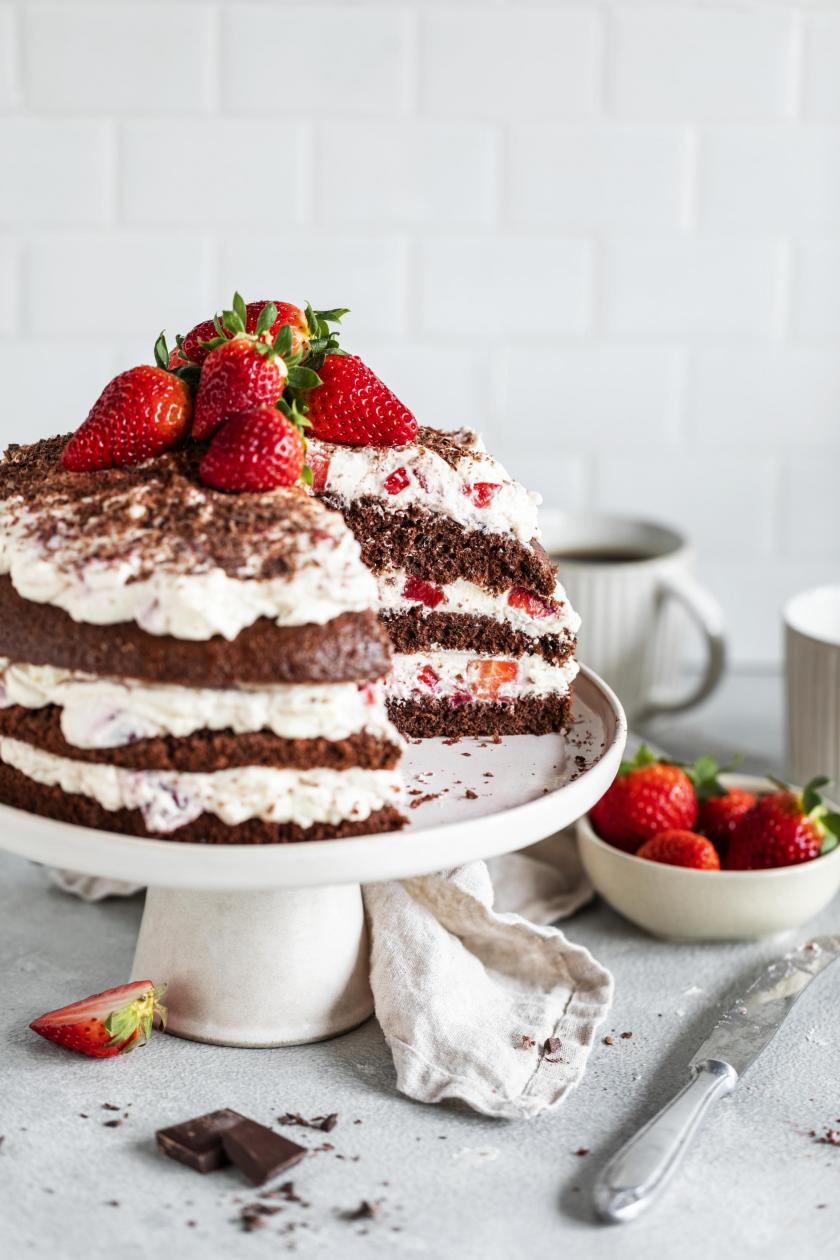 Schwarzwälder Erdbeertorte angeschnitten auf einer Kuchenplatte