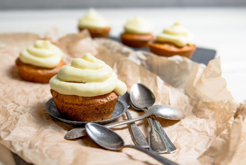 Carrot Cupcakes mit Frosting auf Backpapier mit angelegten Löffeln.