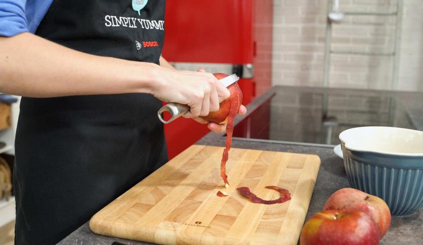 Apfel-Walnuss-Kuchen wird ein Apfel geschält.