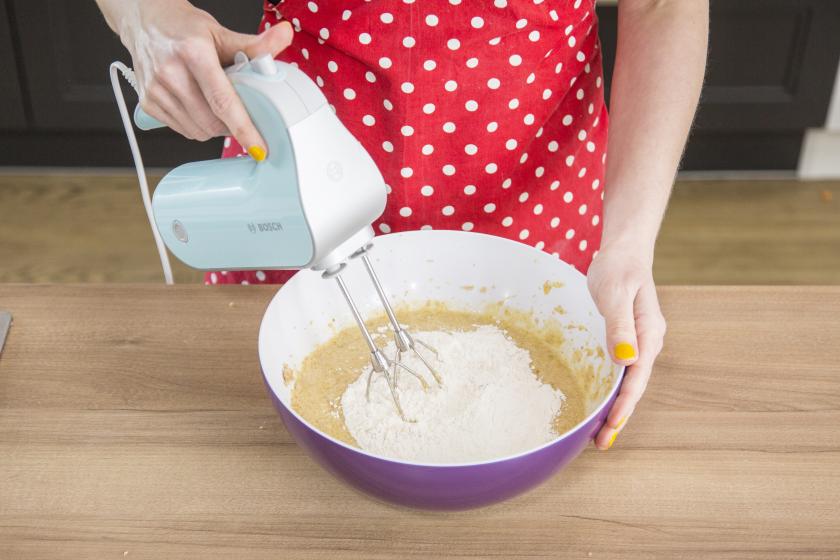 Mehlmischung wird unter den Teig für den Bananenkuchen mit einer Handmixer gerührt.