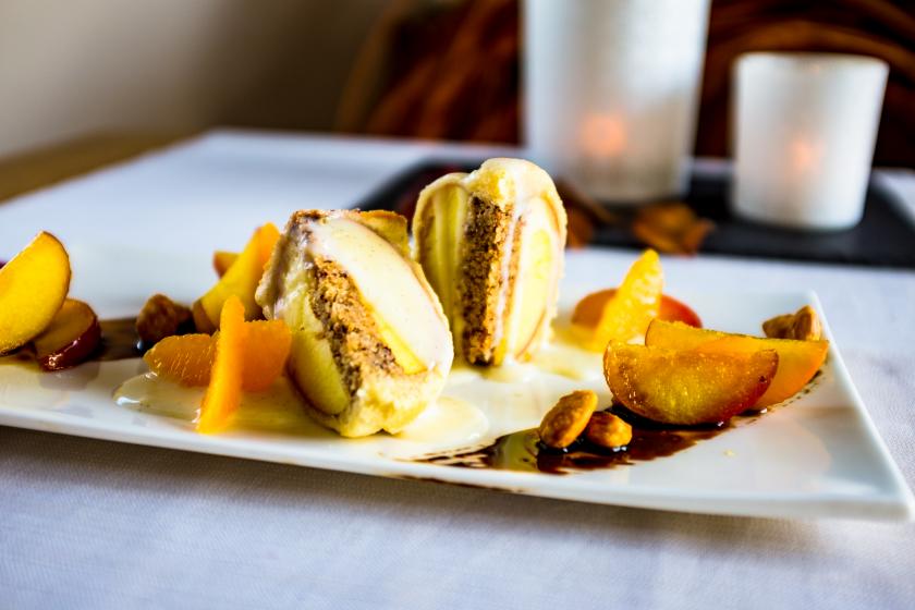 Apfel im Schlafrock halbiert und auf Teller mit Vanillesoße und Orangenfilets angerichtet.