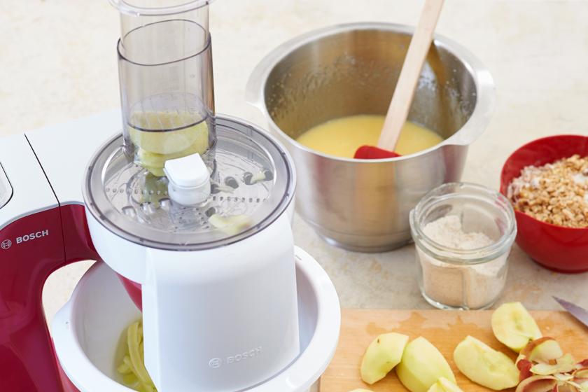 Für die Apfel-Walnuss-Torte werden Äpfel in einer Küchenmaschine gerieben.