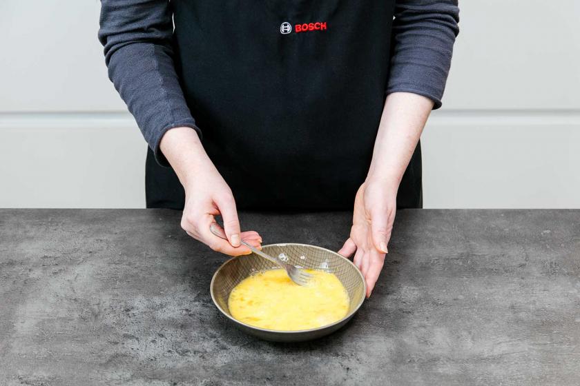 Für die Panade der Arancinis werden Eier verquirlt.