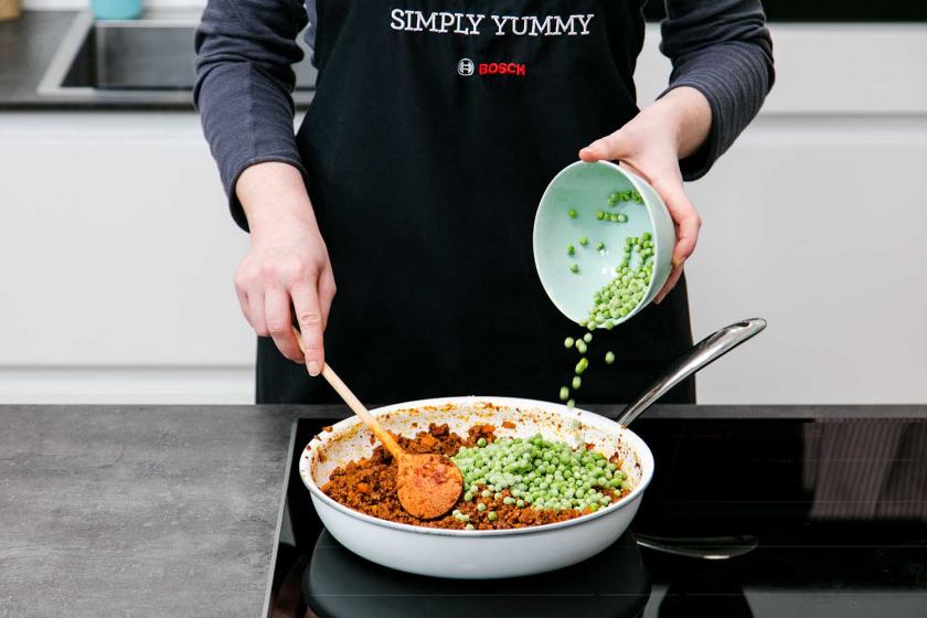 Zur Füllung der Arancini kommen Erbsen in die Pfanne. 