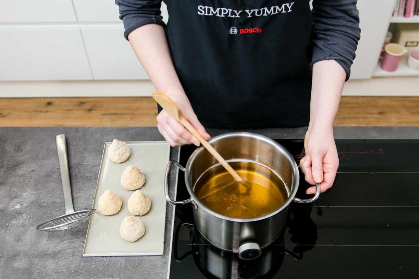Mit einem Holzstab wird das Öl getestet, ob es schon heiß genug ist für die Arancini.