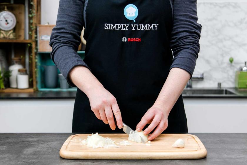 Für Arancini werden Zwiebeln geschnitten.